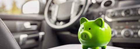 Green piggy bank in car for cost of living crisis